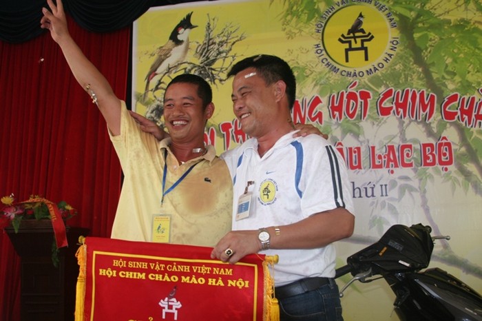 Ông Nguyễn Quốc Toản (bên phải) trao phần thưởng cho một hội viên trong lần thi chim chào mào tại Hà Nội