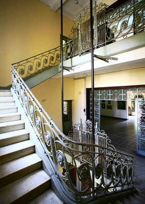 Cầu thang với lan can sắt uốn rất cầu kỳ, ở giữa giếng thang bộ là nơi đặt thang máy.