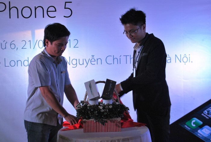 Đại diện Công ty CP dịch vụ số DVS DIGITAL ông Bùi Mạnh Tuấn (bên phải) và đại diện SHOP DUNK giới thiệu hai chiến điện thoại iPhone 5.