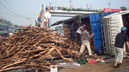 Đội cứu hộ rỡ số lượng gỗ trên thùng xe xuống để giải tỏa chiếc xe tải gặp nạn