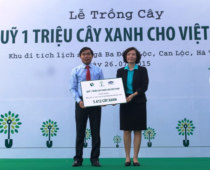 Đại diện Vinamilk, bà Bùi Thị Hương - Giám đốc Điều hành Vinamilk trao tặng biểu tượng 5.612 cây xanh sẽ được trồng tại Khu di tích lịch sử Ngã ba Đồng Lộc cho đại diện Ban quản lý di tích.