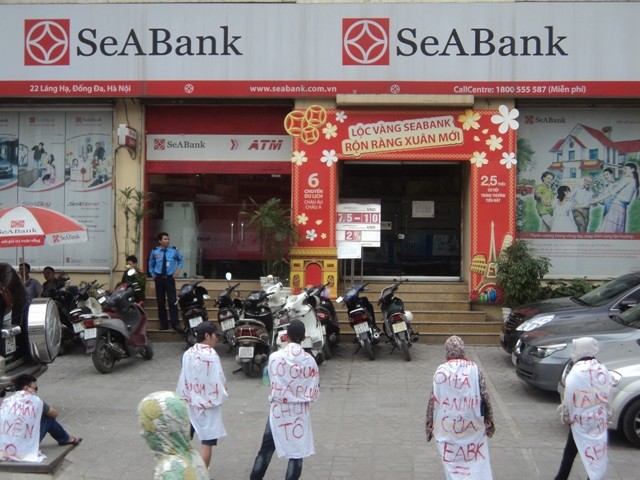 Một số người dân đeo băng rôn quanh mình trước SeaBank Láng Hạ (Ảnh: Quang Tuệ)