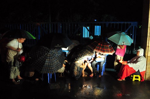Rất đông phụ huynh xếp hàng dầm mưa suốt đêm trước cổng trường PTCS Thực Nghiệm, quận Ba Đình tối 11/5 chờ đến 6h sáng hôm sau để được mở cửa vào mua hồ sơ xin học lớp 1 cho con.