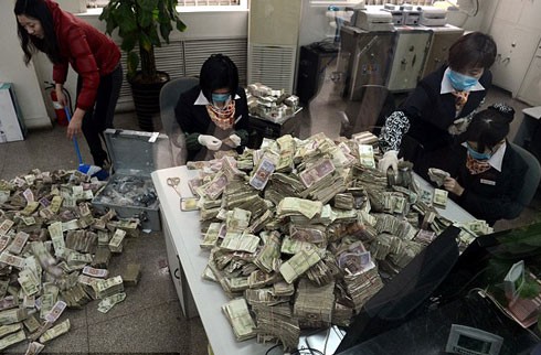 Các nhân viên ngân hàng đang ngồi phân loại số tiền lẻ được chất đống do một khách hàng mang đến để gửi tiết kiệm. Ảnh: China Foto Press