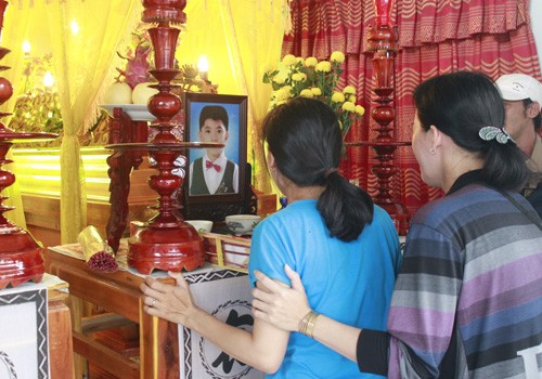 Chị Huỳnh Thị Thanh Thảo (mặc áo xanh), vợ anh Lộc và mẹ bé Tài, khóc nức nở bên ảnh và quan tài chồng, con.