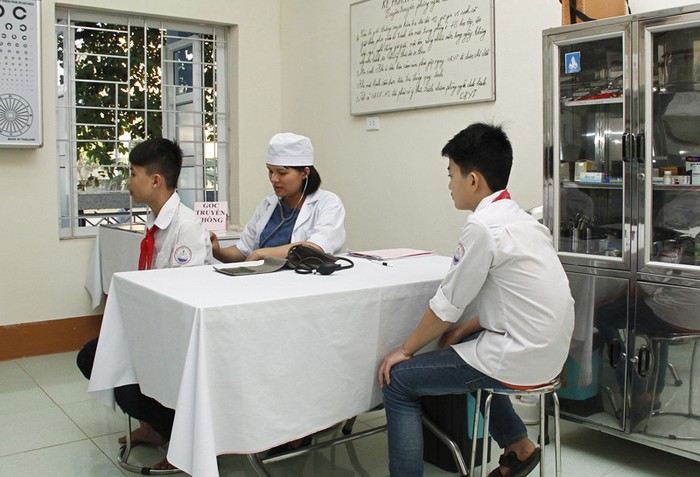 Nhân viên y tế trường học đang chăm sóc sức khỏe cho học sinh (Ảnh: Báo Hòa Bình).