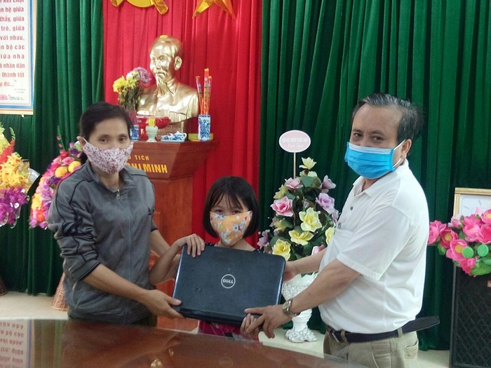 Thầy Trần Trọng Ninh, Hiệu trưởng nhà trường đang trao máy tính cho học sinh về học trực tuyến (Ảnh nhà trường cung cấp)