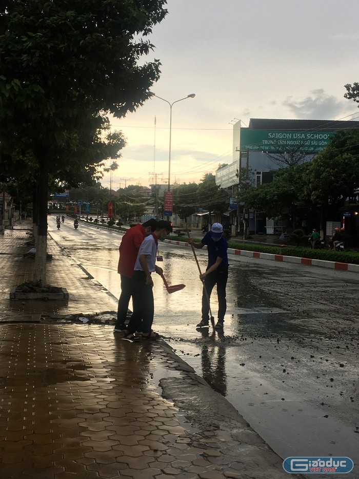 Thầy giáo và học sinh đội tình nguyện quét rác, xúc cát sau cơn mưa lớn (Ảnh Phan Tuyết)