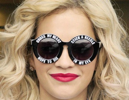 Đầu tiên phải kể đến ngôi sao nhạc Pop - Rita Ora bởi chiếc kính tròn in sologan trắng vô cùng độc đáo. Nữ ca sĩ đã kiêu hãnh đeo chiếc kính thể hiện “cái tôi” có đôi chút cuồng nhiệt và nổi loạn khi tham dự một Show truyền hình của BBC.