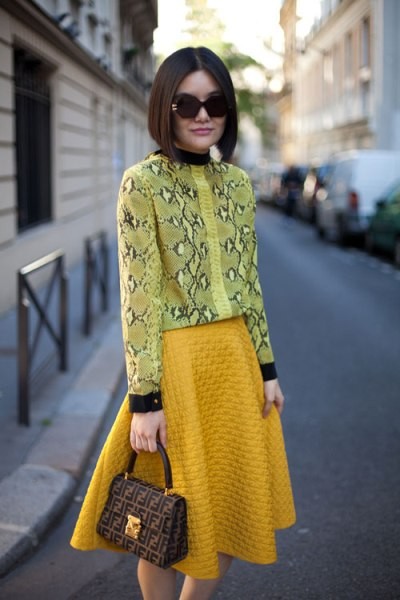 Chiếc áo họa tiết da rắn màu vàng chanh kết hợp với chân váy màu vàng mustard tạo nên một bộ đồ "tone sur tone".