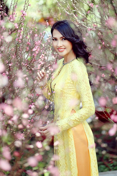 Người mẫu - diễn viên Anh Thư với chiếc áo dài ren sắc mai tạo dáng tươi tắn bên hoa đào.