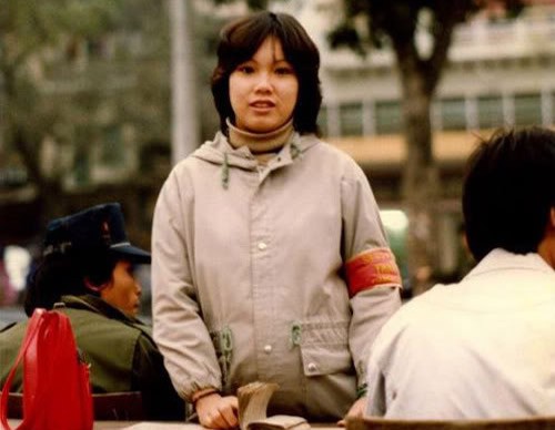 Thiếu nữ "băng đỏ" xinh đẹp với một trong những cách mặc thời trang nhất giữa thập niên 80: Áo len cổ lọ bên trong, áo lông Đức bên ngoài. Người ngồi bên cạnh cũng rất hợp thời cùng áo Nato và mũ bò kiểu Levi's