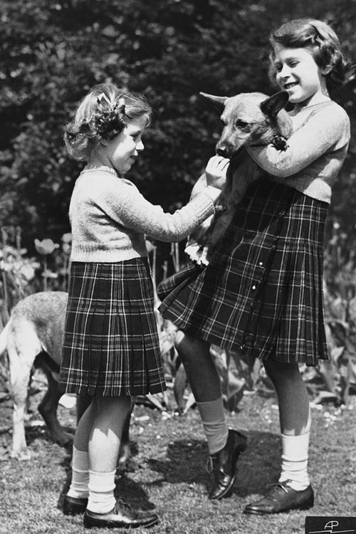 Tháng 7/1936, công chúa Elizabeth (phải) cùng em gái Margaret chơi trong vườn nhà. Cả hai cùng mặc trang phục váy xếp nếp kẻ ca rô và áo len.