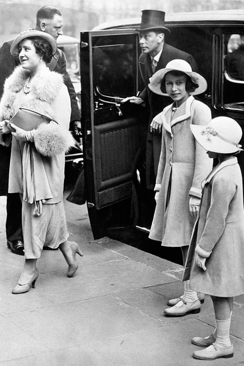 Công chúa Elizabeth, khi 11 tuổi, cùng em gái Margaret theo bố mẹ - vua George VI và nữ hoàng Elizabeth - tới dự buổi hòa nhạc cho trẻ em ở nhà hát Central Hall, Westminster, Anh. Hai chị em cùng diện áo khoác dáng váy và mũ rộng vành có dải ruy băng đính vòng quanh mũ.