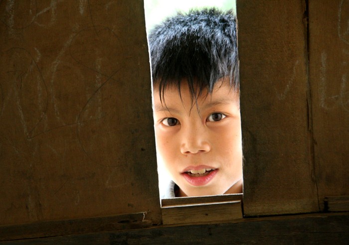 Ánh nhìn của em học sinh điểm trường tiểu học Làng Cò qua khe hở lớp học.