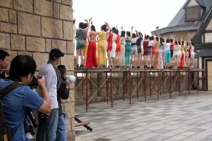 Các thí sinh được ghi hình vẫy tay chào trên một chiếc cầu dựng tạm, bên dưới -phía bên kia bức tường là một khoảng không hun hút.
