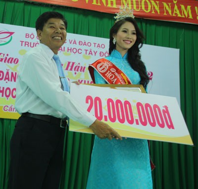 Ông Phan Văn Thơm, Quyền Hiệu trưởng nhà trường, trao tặng 20 triệu đồng cho Hoa hậu Đặng Thu Thảo. Ảnh: Người Lao Động