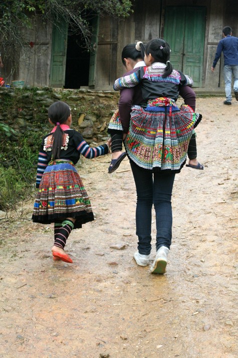 Hình ảnh Ngọc Hân chơi đùa và cõng học sinh miền núi qua quãng đường trơn trượt.