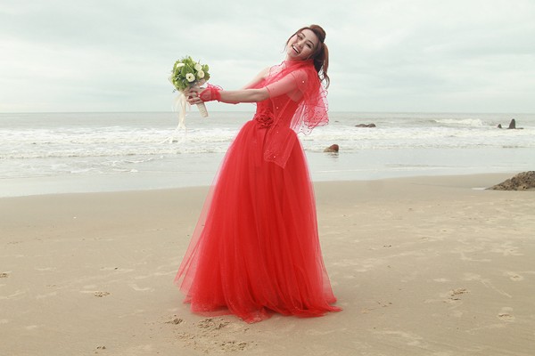 Phía sau máy quay, Ngân Khánh tinh nghịch tạo dáng trong bộ váy cưới màu đỏ rực rỡ.