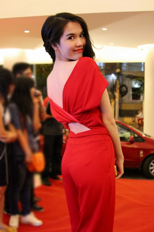 Ngọc Trinh mặc bộ jumpsuit đỏ và tô son cùng màu rực rỡ. Cô tạo dáng khoe lưng trần quen thuộc.