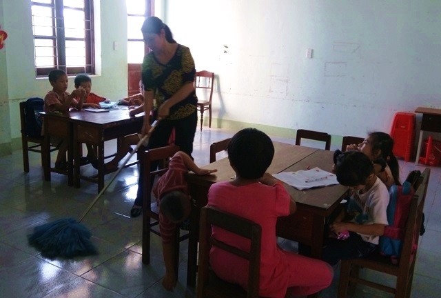 Vừa dạy học, cô Võ Thị Huế vừa lau nhà vì nhiều em chưa thể tự đi vệ sinh (Ảnh: Thủy Phan)