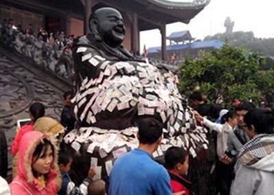 Hối lộ thánh thần không còn là chuyện hiếm gặp. Trong ảnh là hình ảnh người đi lễ phủ tiền lẻ lên tượng ở Chùa Bái Đính, Ninh Bình (Ảnh vietnamnet)