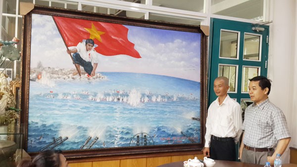 Họa sĩ Bùi Lệ Trang (trái) và ông Nguyễn Văn Phước - Giám đốc First News giới thiệu bức tranh “Gạc Ma - Vòng tròn bất tử”. (Ảnh: cand.com.vn)