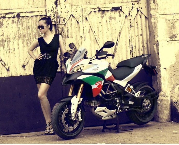 Sánh vai cùng chiếc xe Ducati 1200Cc, người đẹp hóa thân thành một cô nàng khá "ngầu" với cặp kính đen, bộ váy đen và một khuôn mặt biểu cảm sắc lạnh