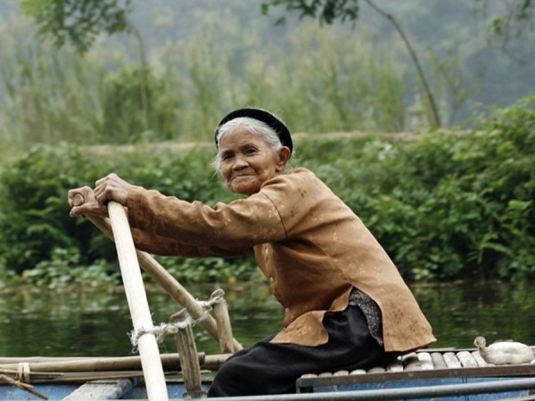 Hình ảnh một cụ già đang chèo thuyền trên dòng sông Ngô Đồng (Hoa Lư, Ninh Bình)