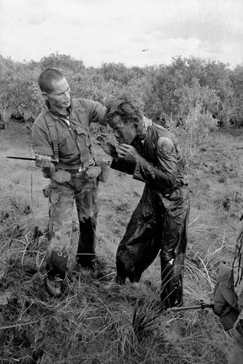 Một lính ngụy sử dụng chuôi dao để đánh một người nông dân vì người này đã cung cấp cho quân đội của chính phủ Việt Nam Cộng hòa những thông tin không chính xác về sự di chuyển của du kích Việt Cộng trong một ngôi làng phía tây Sài Gòn. Bức ảnh được chụp vào tháng 1 năm 1964.