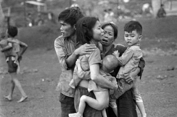 Tháng 6 năm 1965: Những thường dân Việt Nam, trong số ít người sống sót trong hai ngày giao tranh ác liệt, đang tụm lại với nhau sau một cuộc tấn công của quân đội chính phủ Việt Nam Cộng hòa nhằm giành lại căn cứ ở Đồng Xoài, Việt Nam.