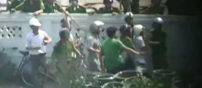 Trong khi nhà báo Nguyễn Ngọc Năm bị còng tay, một số người bên ngoài, đeo băng đỏ ở tay, dùng gậy dài để tiếp tục đánh vào đầu nhà báo.