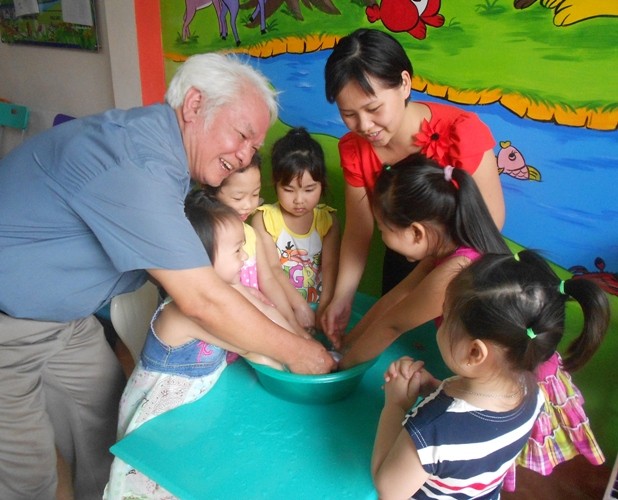 Tiến sĩ Nguyễn Văn Khải trong một buổi chữa bệnh tay- chân- miệng cho các cháu nhỏ ở trường mầm non