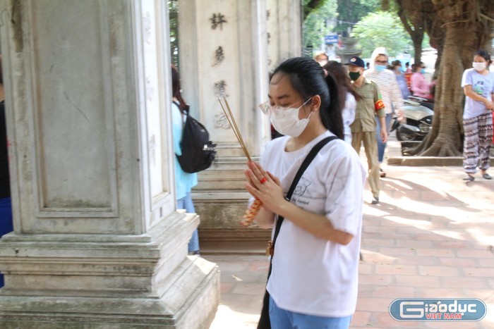 Nữ sinh này chọn cách cầm hương, chắp tay, nhắm mắt và đi vòng tròn xung quanh những trụ bê tông trước cổng Văn Miếu đề cầu may mắn trong kỳ thi năm nay.