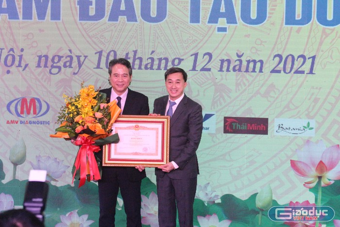 Giáo sư Trần Văn Thuấn - Thứ trưởng Bộ Y tế, thừa ủy quyền của Thủ tướng Chính phủ trao cờ thi đua và bằng khen cho đại diện Trường đại học Dược Hà Nội. Ảnh: Trung Dũng