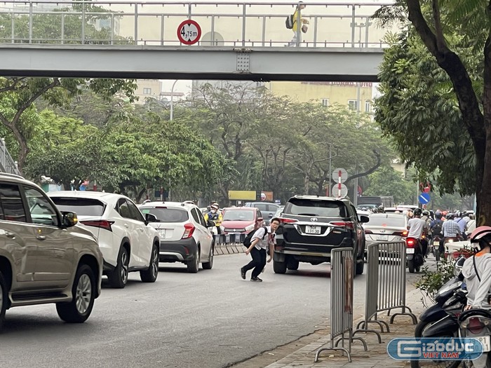 Một học sinh băng qua đường giữa dòng xe tấp nập, dù ngay cạnh đó có cầu vượt đi bộ. Ghi nhận tại phố Nguyễn Khánh Toàn (quận Cầu Giấy), trước cổng Trường Trung học cơ sở Dịch Vọng.