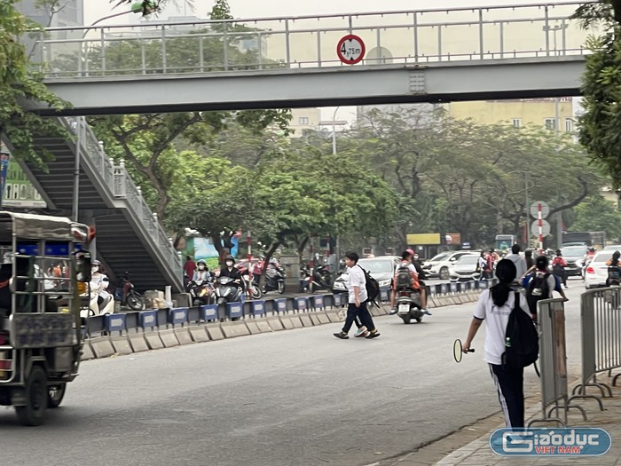 Học sinh qua đường tại đường Nguyễn Khánh Toàn, ngay dưới chân cầu vượt đi bộ.