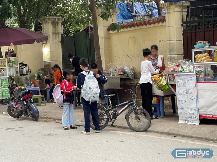 Học sinh Trường Tiểu học Mễ Trì mua đồ ăn được bán ở các hàng ở trước cổng trường. Ảnh: T.D