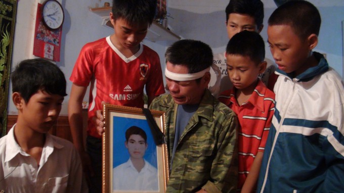 Ông Nguyễn Văn Điều khóc bên di ảnh con trai Nguyễn Văn Nam và năm học sinh được Nam cứu sống - Ảnh: Vũ Toàn