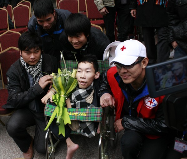 Anh bất ngờ tặng hoa và chụp ảnh kỷ niệm với một người tàn tật. Cử chỉ đẹp này gây ấn tượng sâu sắc với người hâm mộ Việt Nam. (Ảnh: Dân Trí)