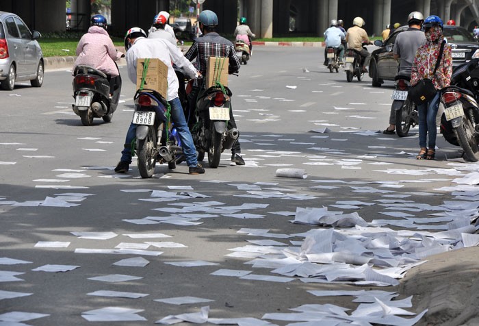 Một lượng giấy lộn lớn bay tung tóe trên mặt đường,