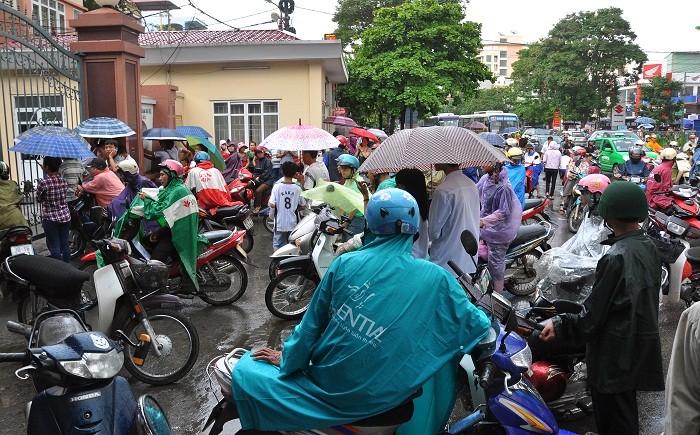 Trước cổng trường ĐH Sư Phạm Hà Nội cũng rất đông các bậc phụ huynh mặc áo mưa, che ô đón con.