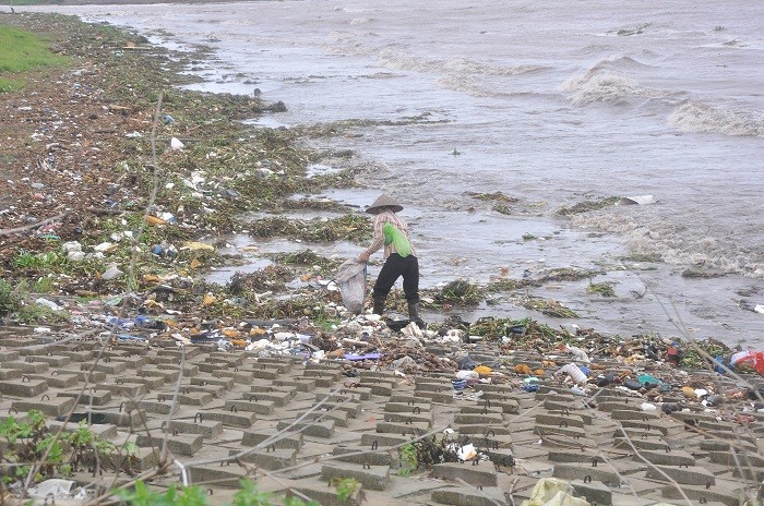 Tranh thủ nước lên, rác đổ vào bãi, người phụ nữ này đi nhặt phế liệu còn giá trị để bán.