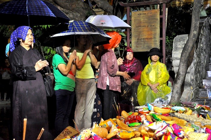 Cơn mưa bất chợt trong lúc lễ dã khiến nhiều người phải đội áo mưa, dùng ô để che