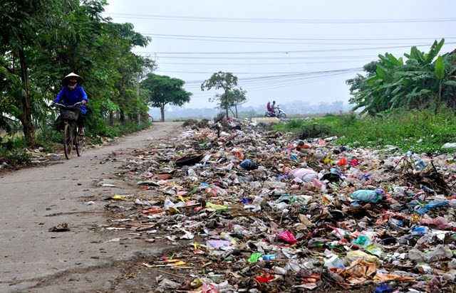 Không chỉ đổ rác xuống bãi tập kết, các tổ thu gom rác và người dân còn đổ ngay trên lòng, lề đường liên xã gây cản trở giao thông.
