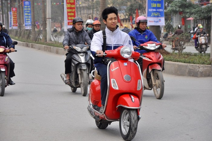 Một nam sinh đầu không mũ bảo hiểm lưu thông bằng xe gắn máy trên đường
