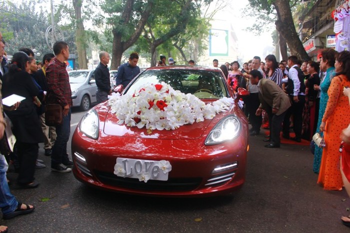 Chiếc xe Porsche màu đỏ được sử dụng làm xe rước dâu. Biển xe được thay bằng tấm bảng dễ thương với chữ &quot;Love&quot; ánh bạc.