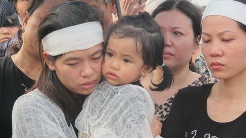 Chị Đinh Thị Xoa (vợ chiến sĩ Nam) ôm cô con gái mới 20 tháng tuổi vào lòng khi bé chưa thể hiểu chuyện gì đang xảy ra… - Ảnh: Thân Hoàng/ Tuổi trẻ