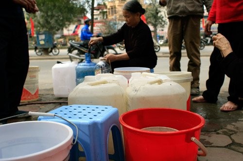Các gia đình xếp hàng chia nhau từng xô nước. Một số hộ dân được trạm dự phòng cung cấp nước. (ảnh Hoàng Nguyên)