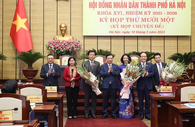 Bí thư Thành ủy Hà Nội Đinh Tiến Dũng (đứng giữa) tặng hoa chúc mừng bà Vũ Thu Hà (áo dài xanh) được bầu làm Phó Chủ tịch Ủy ban Nhân dân thành phố Hà Nội. (Ảnh: PV/Vietnam+)